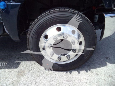 Front wheel of a Chevrolet Silverado 6500HD with chrome hub and radial tire, visible wheel lug nuts and fender.