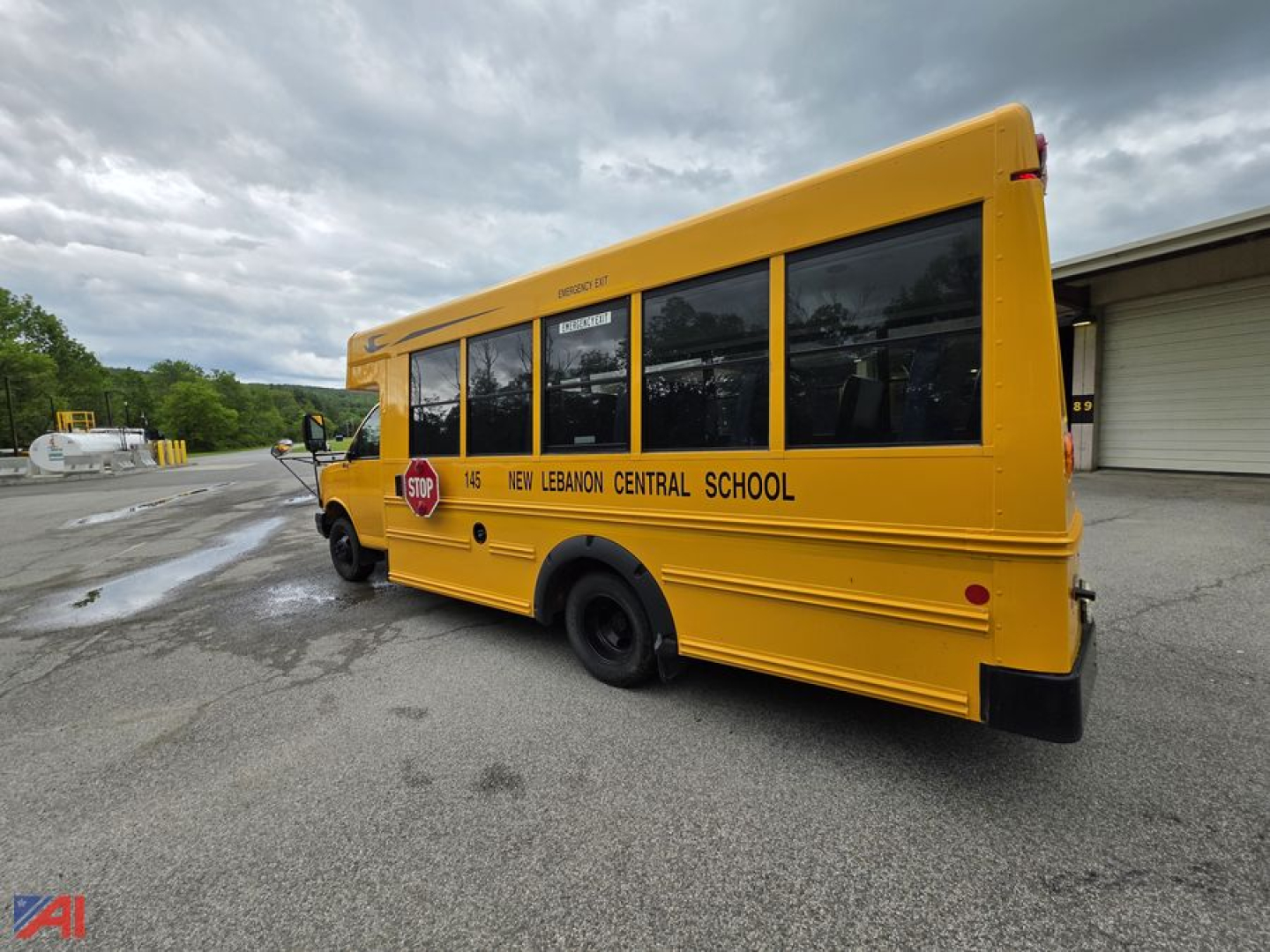 Side view of a yellow 2014 Chevrolet Express G4500 mini school bus with bus lettering New Lebanon Central School and a stop sign graphic on the side.