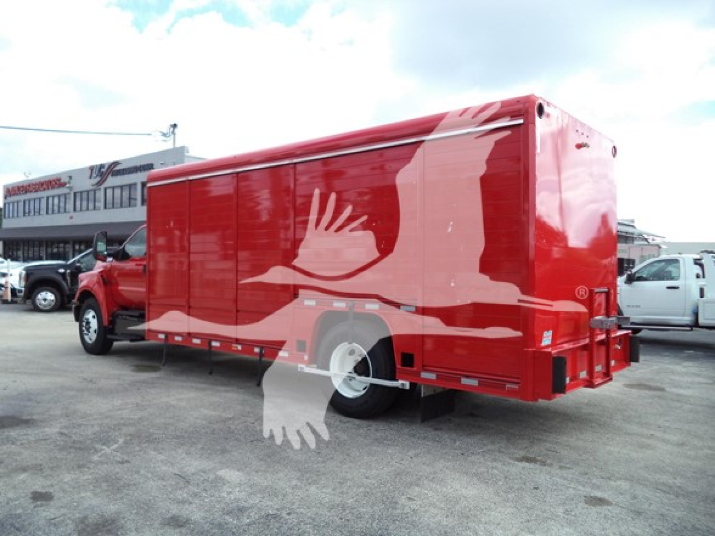 Truck side view showing a red beverage-box truck with white graphics and a mid-2020s Ford F650 chassis.