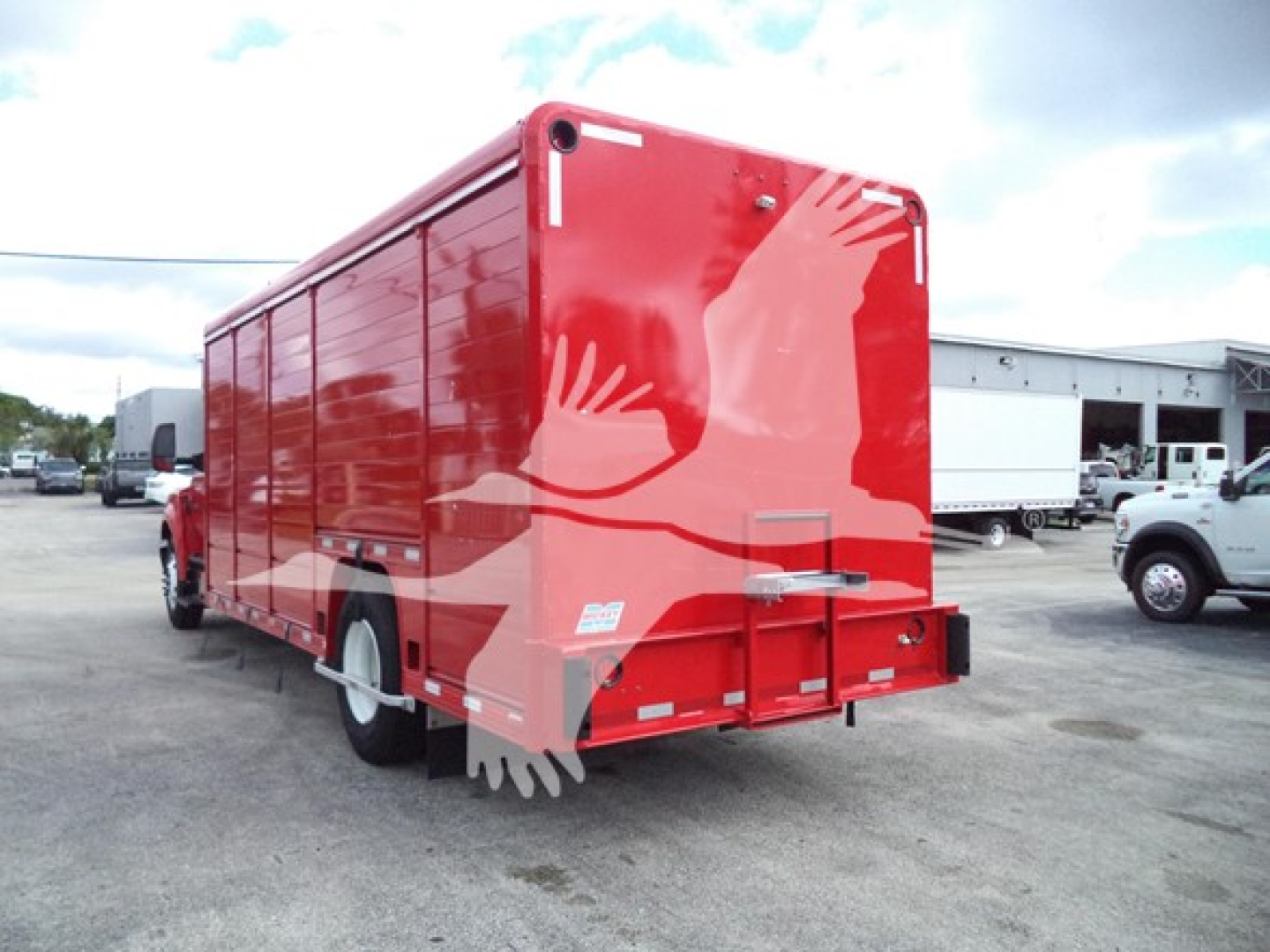 Back view of a red Ford F650 beverage truck with graphic white silhouettes on the sides and rear, showing cargo body and rear bumper.