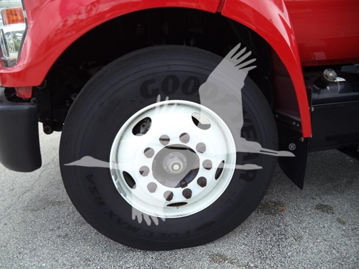Truck front wheel area showing Goodyear tire with white steel wheel and red fender.