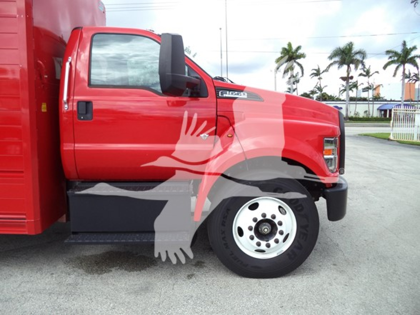 Ford F-series cab and front wheel area of a red 2021 Ford F650 truck showing front fender and wheel with a white overlay graphic.