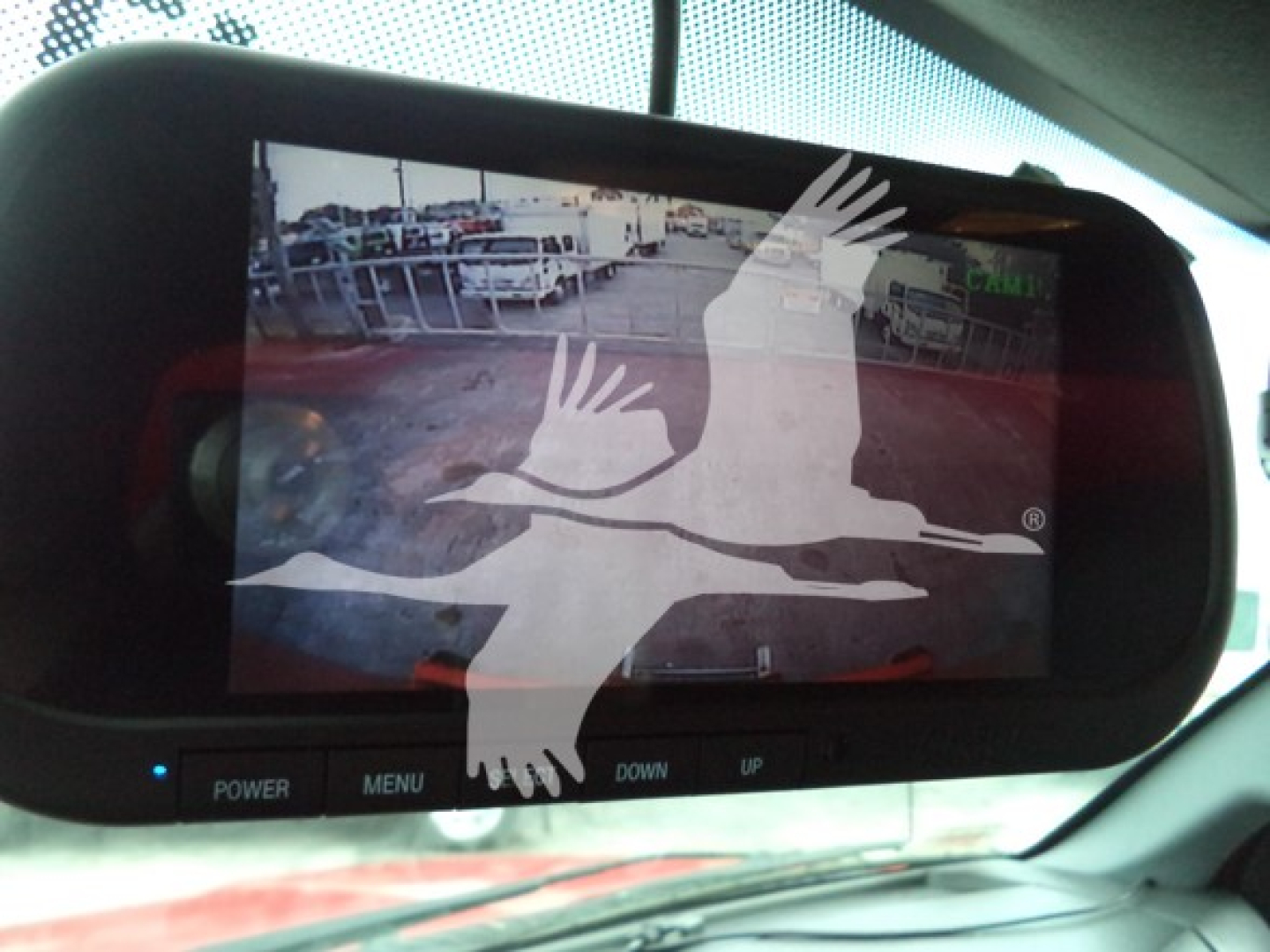 Rearview monitor displaying a grainy image of a truck lot inside the Ford F650, with blue control buttons labeled POWER MENU DOWN UP beneath the screen.