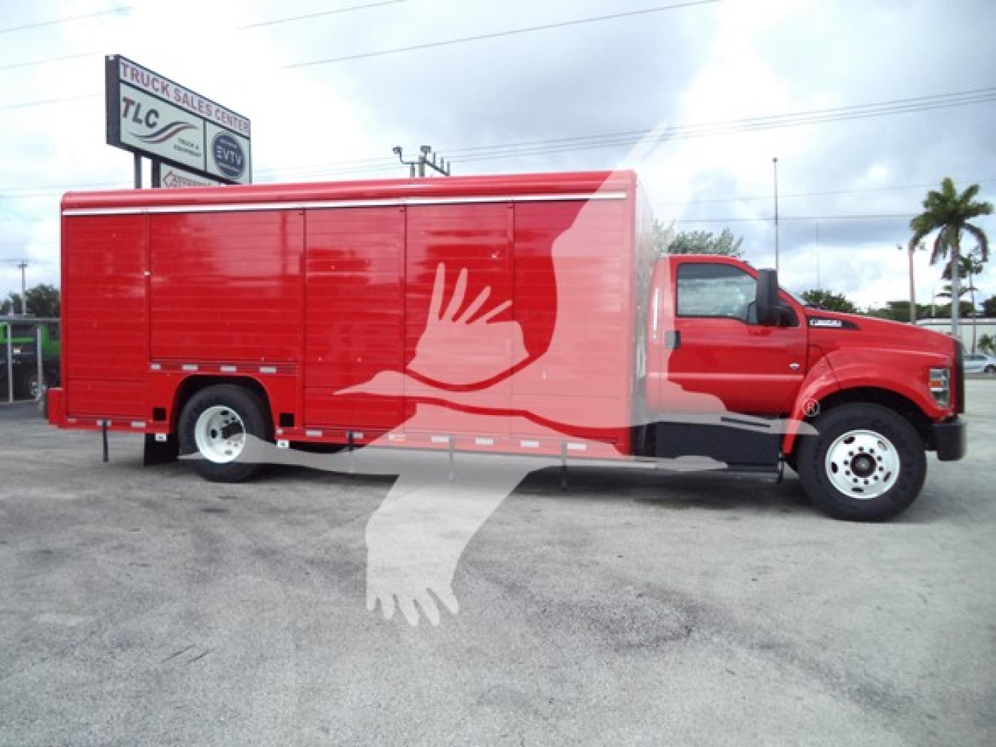 Truck vechicle side view showing large red beverage delivery truck with white crane-like logo on side and a raised L-shaped white graphic on the cargo box.
