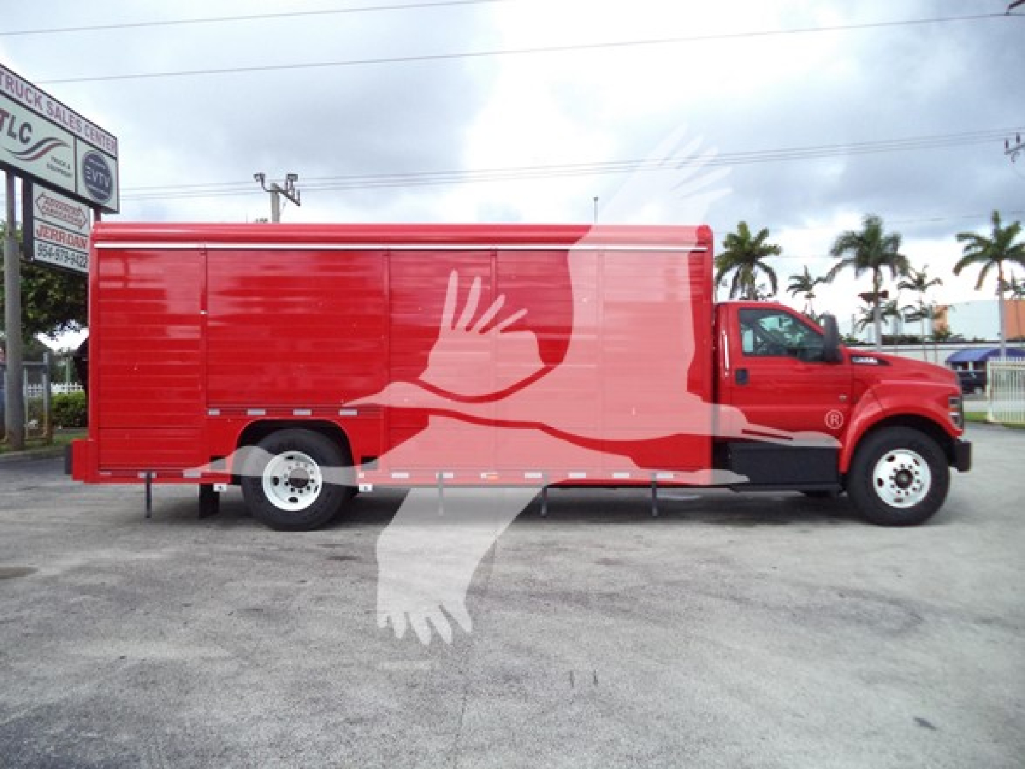 Ford F-650 Sd beverage truck in red with graphic hands on side, side view showing cargo area and cab.