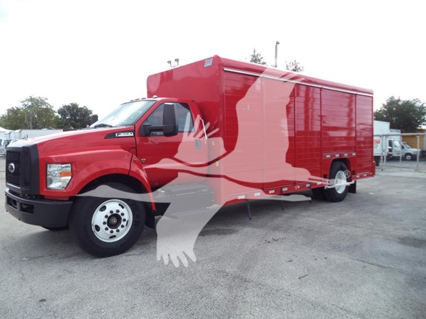 Ford F-650 service truck with red cargo box, side view showing large enclosed rear compartment and cab; clear front grille and wheel; no visible text on body.