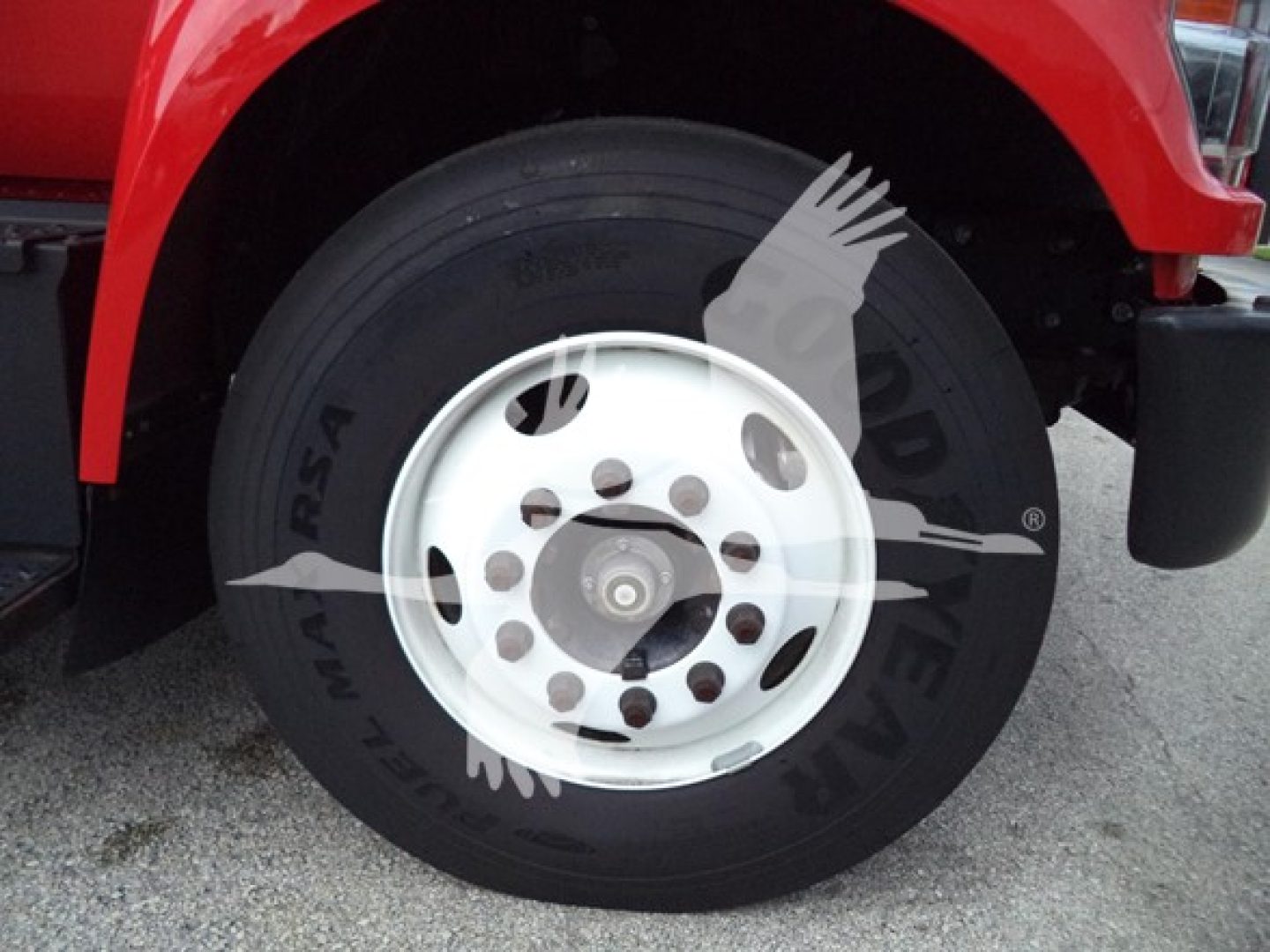 Truck wheel close-up showing front tire and white steel rim; No visible text on the tire clearly readable due to watermark overlay.