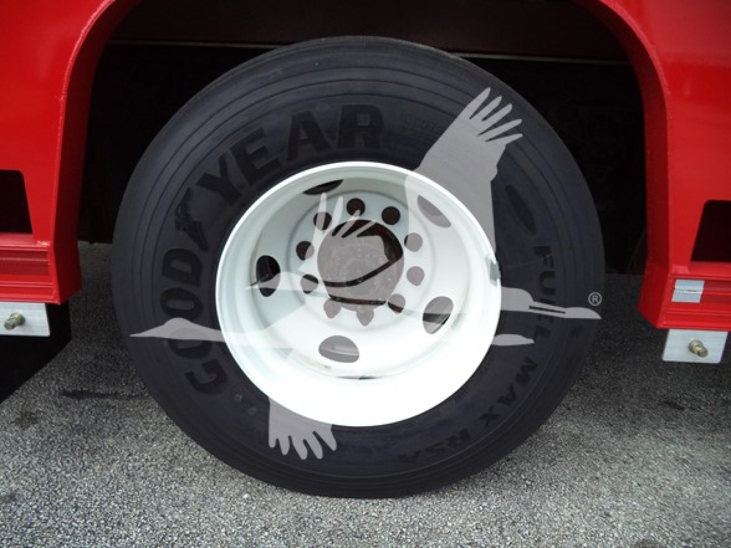 Ford F-Series truck wheel shown with Goodyear tire and white steel rim, partial red fender in view.
