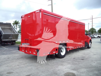 Ford F650 medium-duty truck with a red cargo body and beverage category listing on the side, rear view showing dual rear wheels.