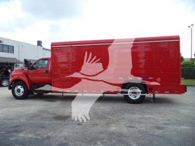 Side view of a red beverage truck with a large white graphic of two hands shaking overlaying the cargo area.