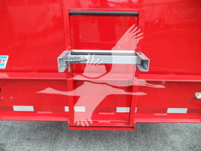 Rear view of a red Ford F650SD truck showing a metal rear latch/step with 'FIRST' branding and a small loading hatch in the tailgate area.