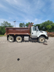 Dump truck side view showing International 7400 with brown dump bed and white cab.