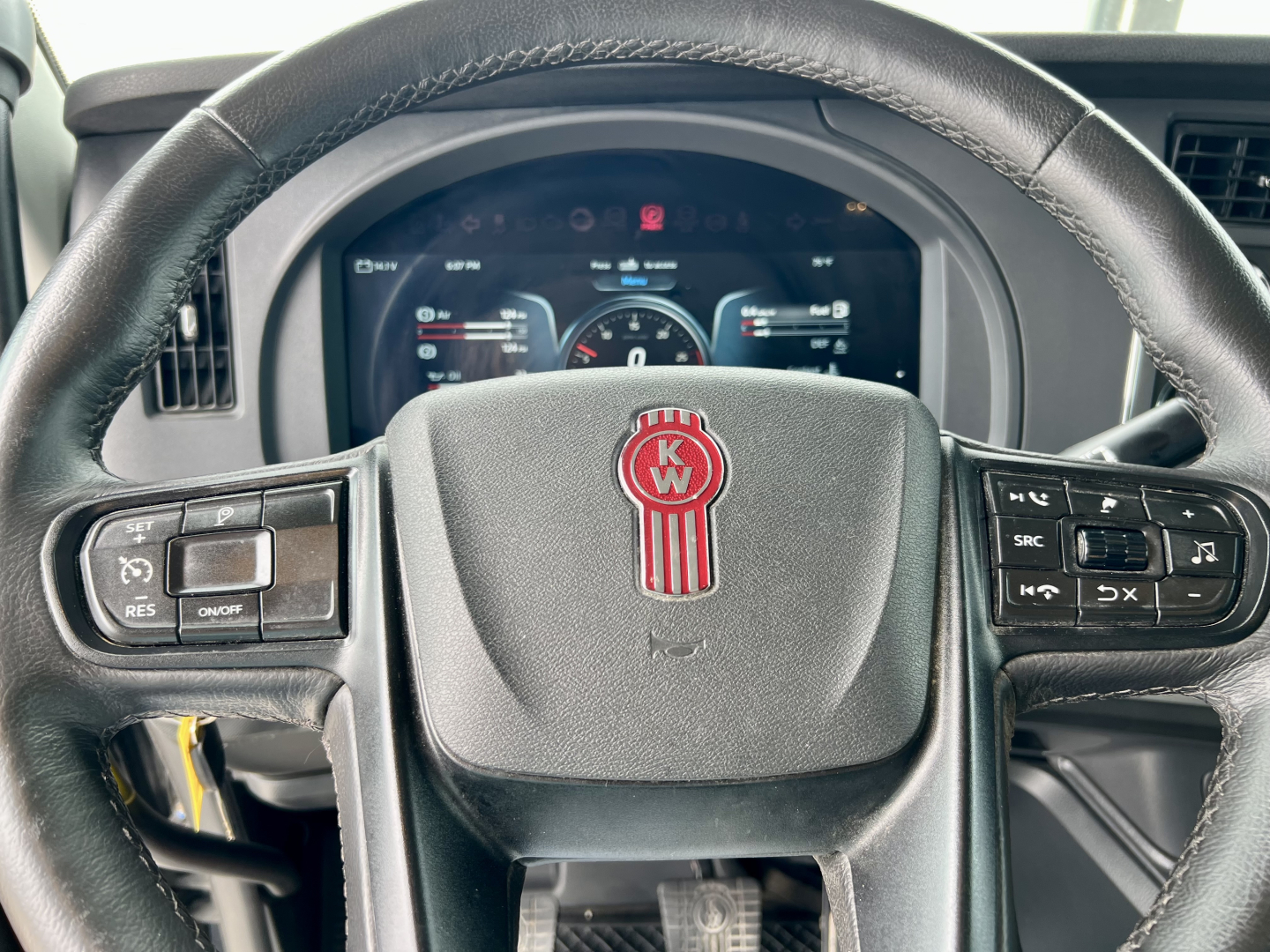Kenworth T880 steering wheel with KW emblem and dashboard visible in the background.