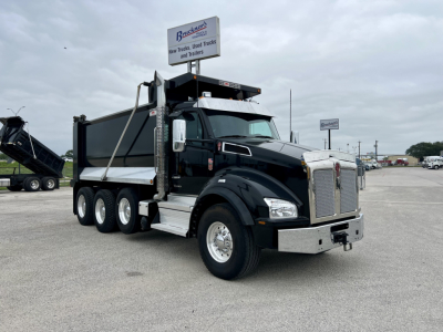 Kenworth T880 dump truck in a parking lot, black cab, 6x4 drive, aluminum dump body, chrome front bumper, side steps, dual rear axles.