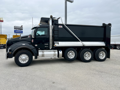 Kenworth T880 dump truck side view showing large dump body and triple rear axles.