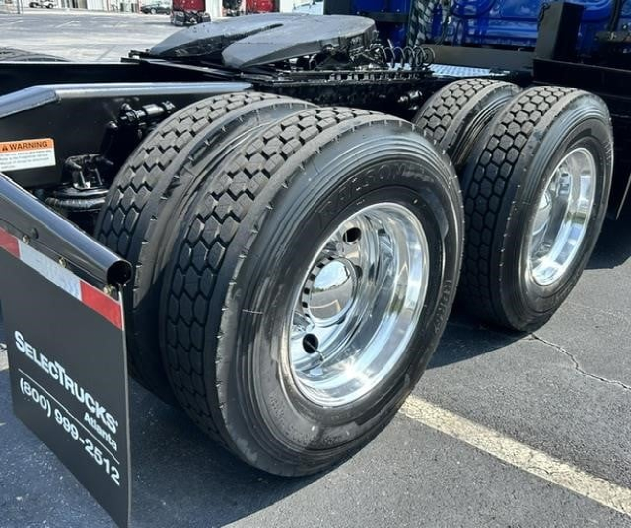 Freightliner Cascadia 126 rear dual axle wheels and tires visible from side showing chrome hubcaps and black chassis with tank trailer hitch.