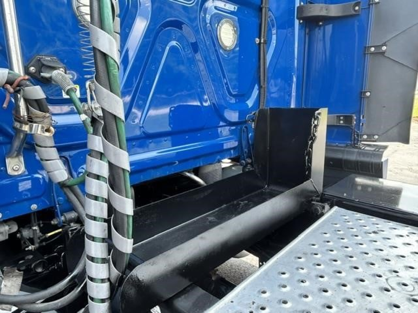 Freightliner Cascadia 126 truck side view showing black exhaust stack and chassis area with perforated aluminum step plate.