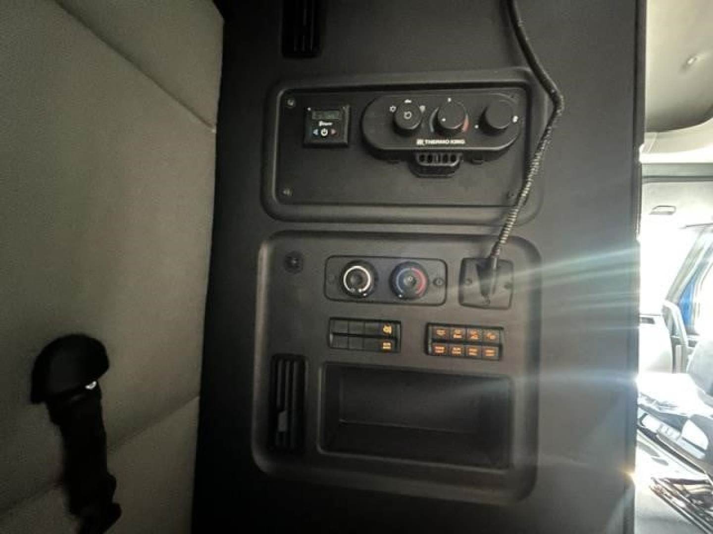 Cab interior panel of Freightliner Cascadia with control knobs and small display, showing vents and switches.