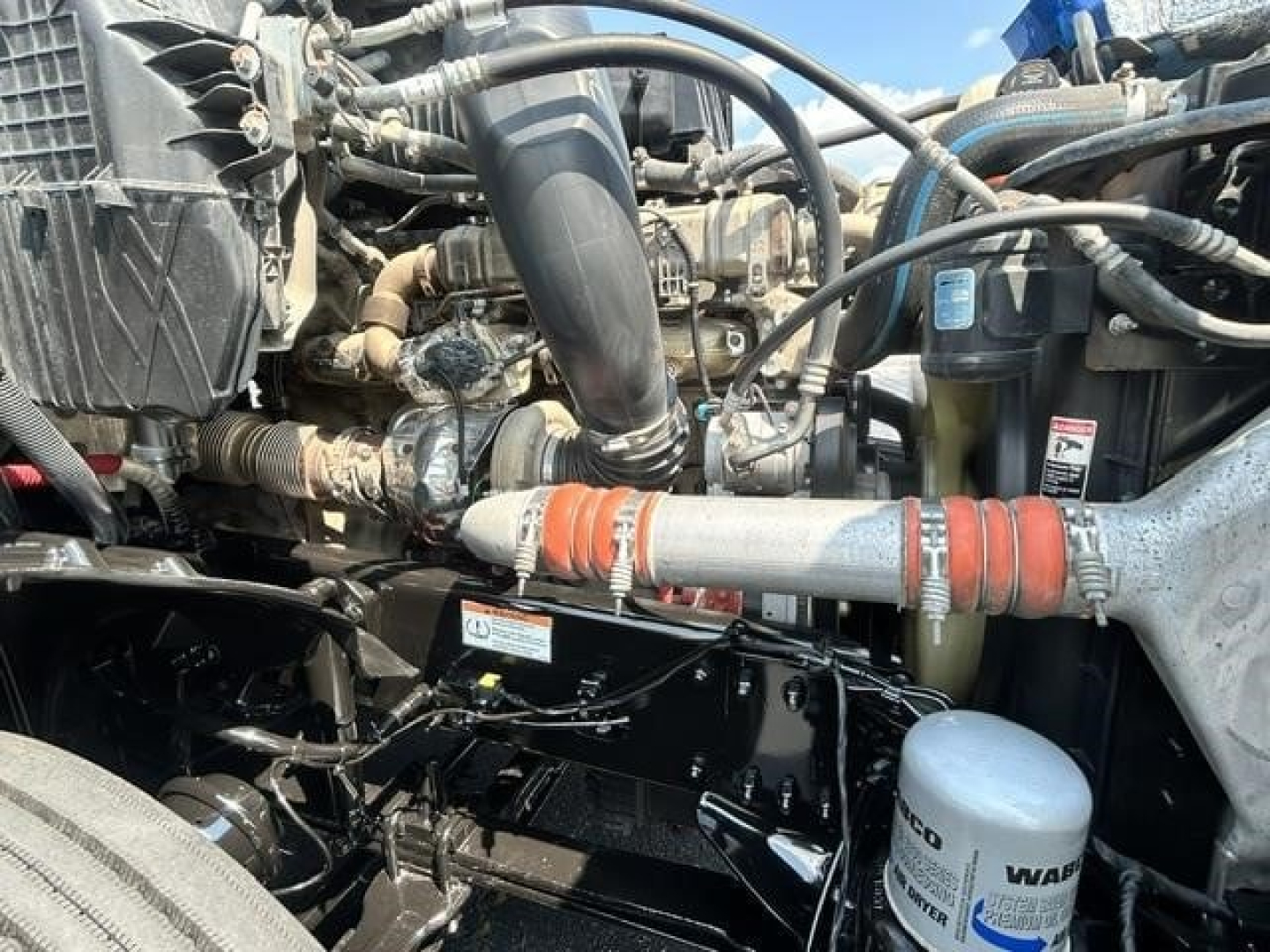 Engine bay of a Freightliner Cascadia shows hoses, coolant reservoir, and various components with visible labels.