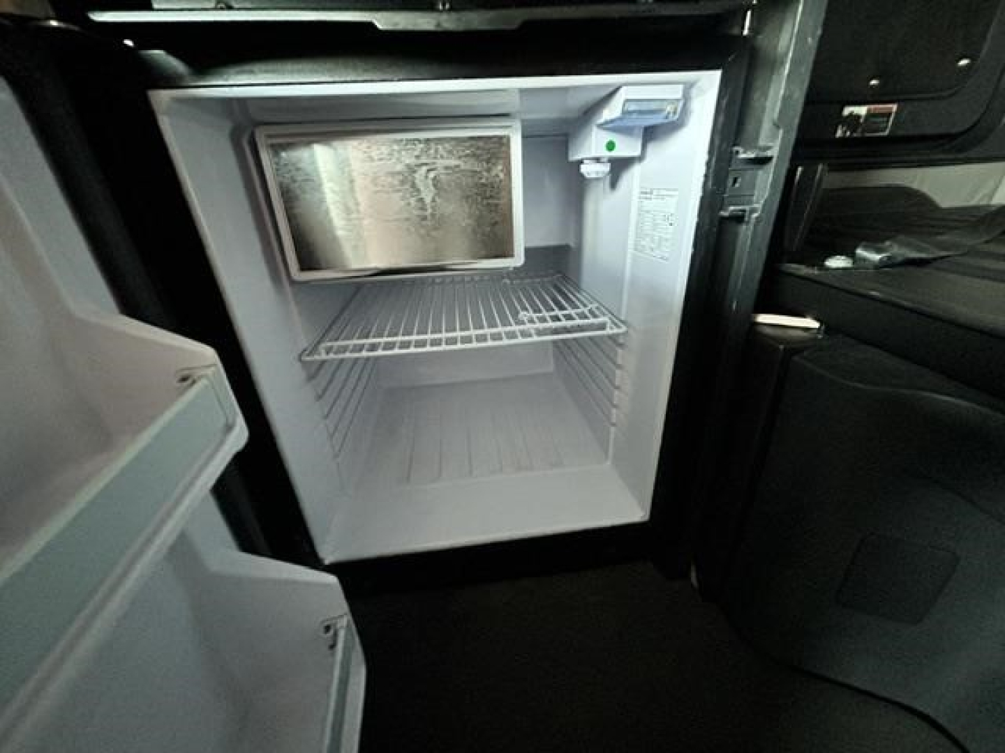Freightliner Cascadia interior kitchenette area with empty mini-fridge/freezer unit and open door