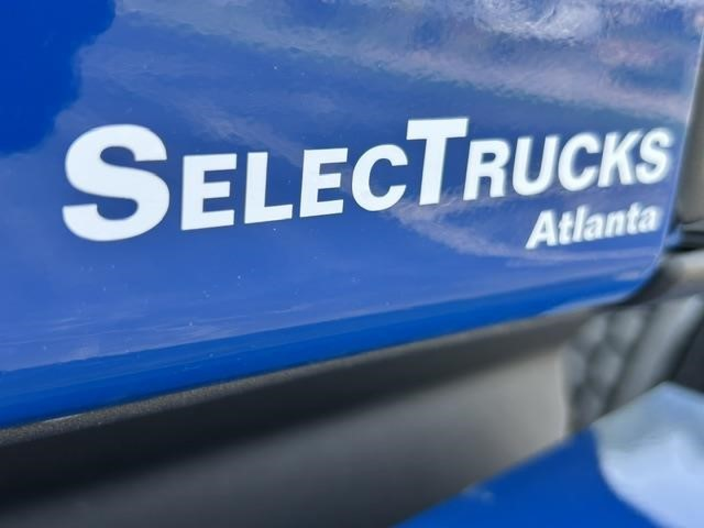 Selective image shows a blue Freightliner Cascadia with SelectTrucks Atlanta logo on the side.