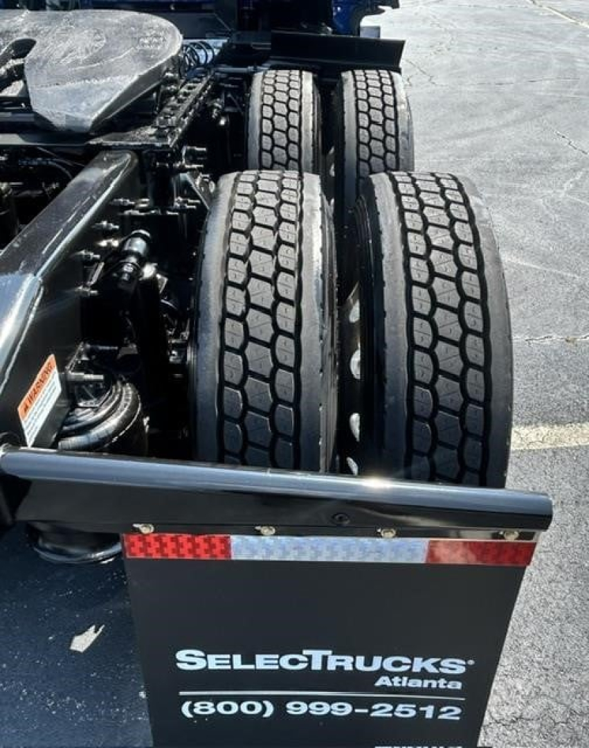 Truck rear chassis with dual rear axles and dual tires visible beneath; SelectTrucks Atalanta logo plate and contact number at rear fender.