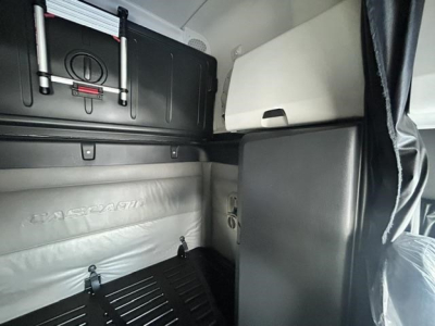 Cabin view of a 2022 Freightliner Cascadia sleeper truck interior showing storage compartments, side panel, and sleeper bunk in metallic gray.