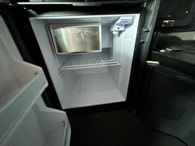 Freightliner Cascadia interior kitchenette area with empty mini-fridge/freezer unit and open door