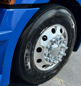 Truck wheel and tire on a blue Freightliner Cascadia 126 cab, chrome hub, 295/75R22.5 tire, outer radius.