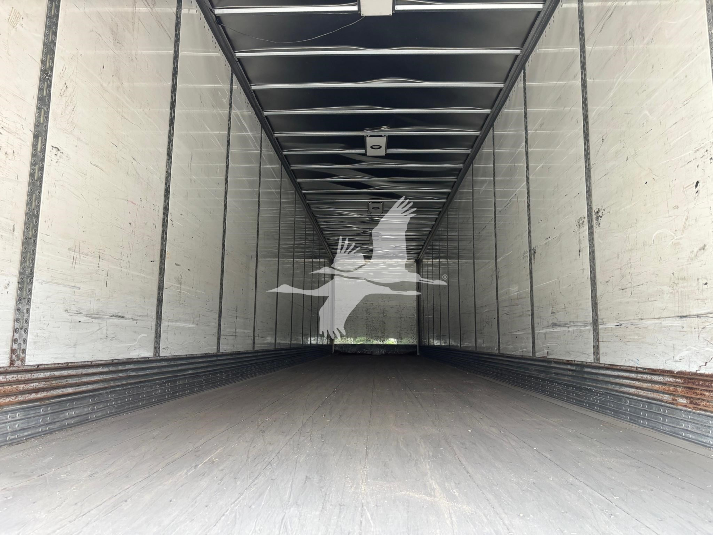 Trailer interior cargo space showing empty long empty trailer with white walls and dark wooden floor