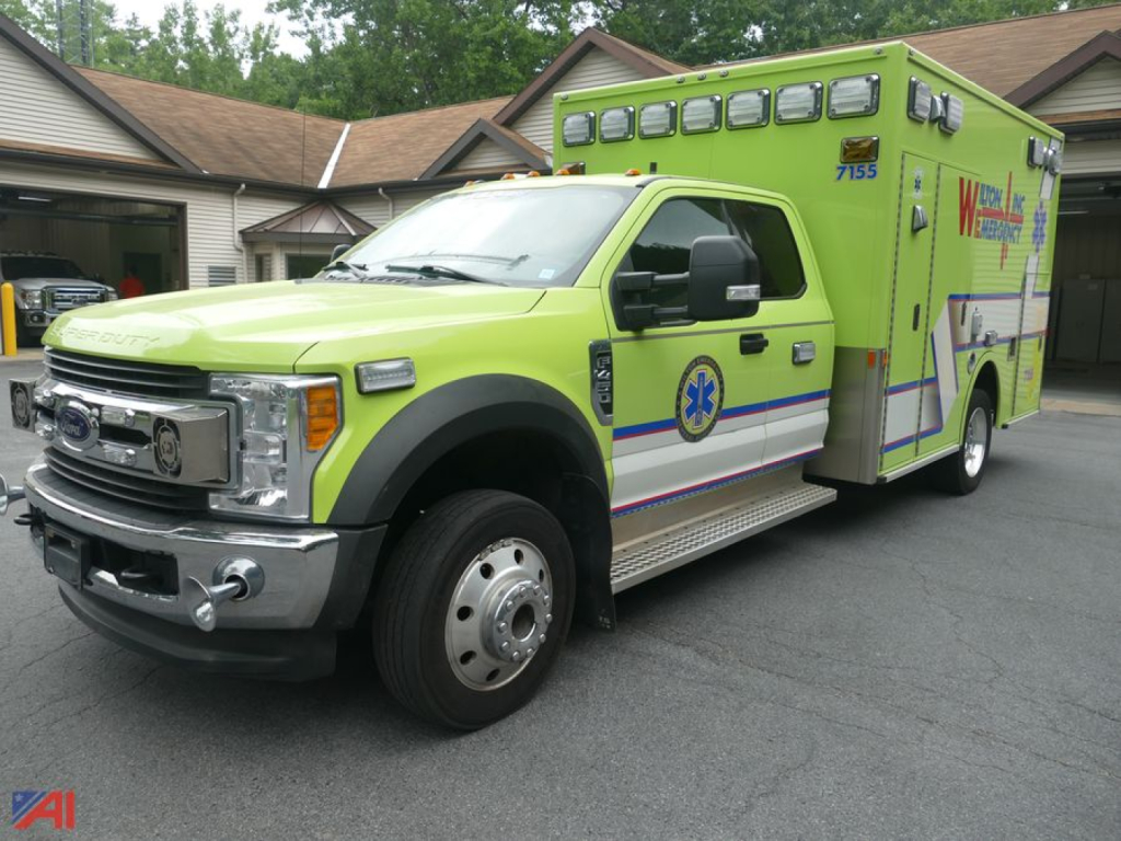 Ambulance vehicle front-left view showing bright lime green Ford F-450 Super Duty with blue stripe emergency markings.