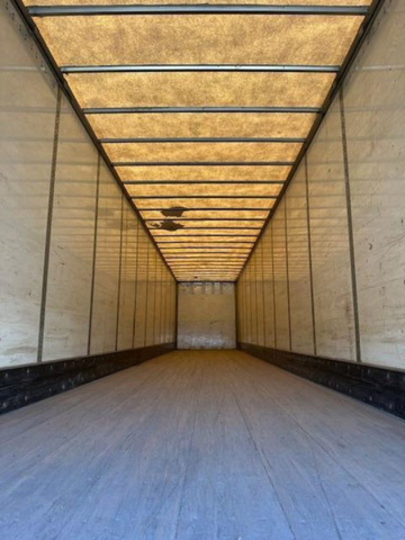 Trailer interior image showing empty Wabash van trailer cargo area with aluminum walls and wooden roof beams, long narrow perspective.