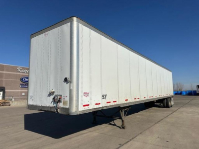 Semi trailer in a parking lot showing a white Wabash box with 53' length marking, rear and side reflective tape, and hitch/kingpin area.