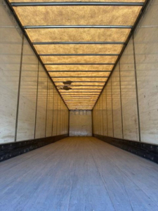 Trailer interior image showing empty Wabash van trailer cargo area with aluminum walls and wooden roof beams, long narrow perspective.