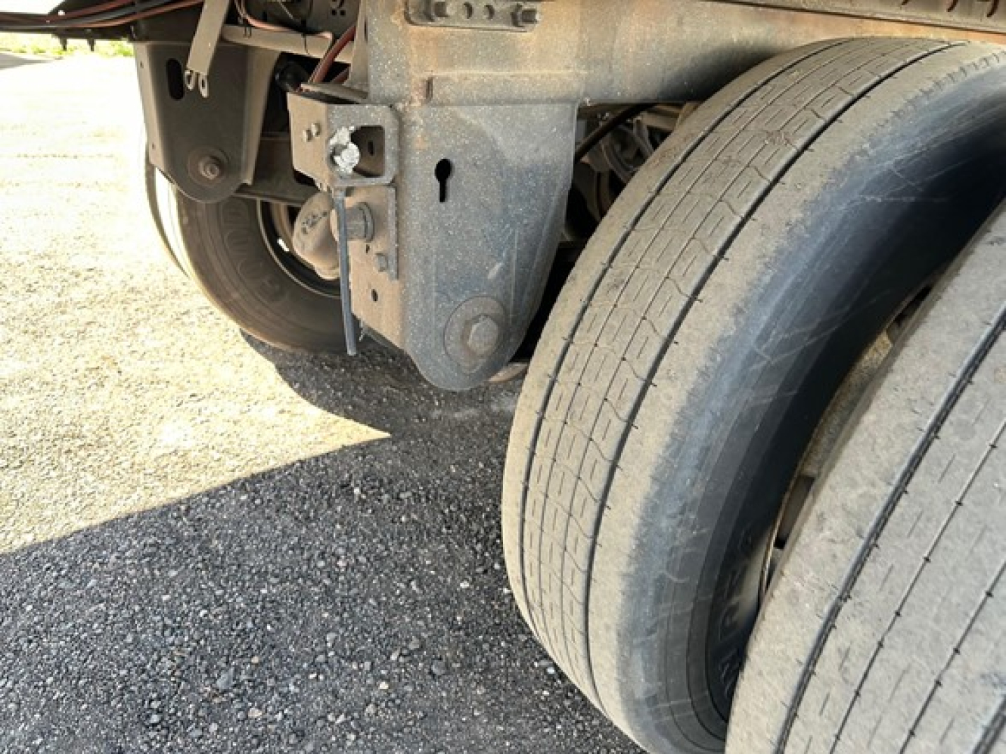 Trailer undercarriage showing dual rear tires and mounting bracket with metal frame components