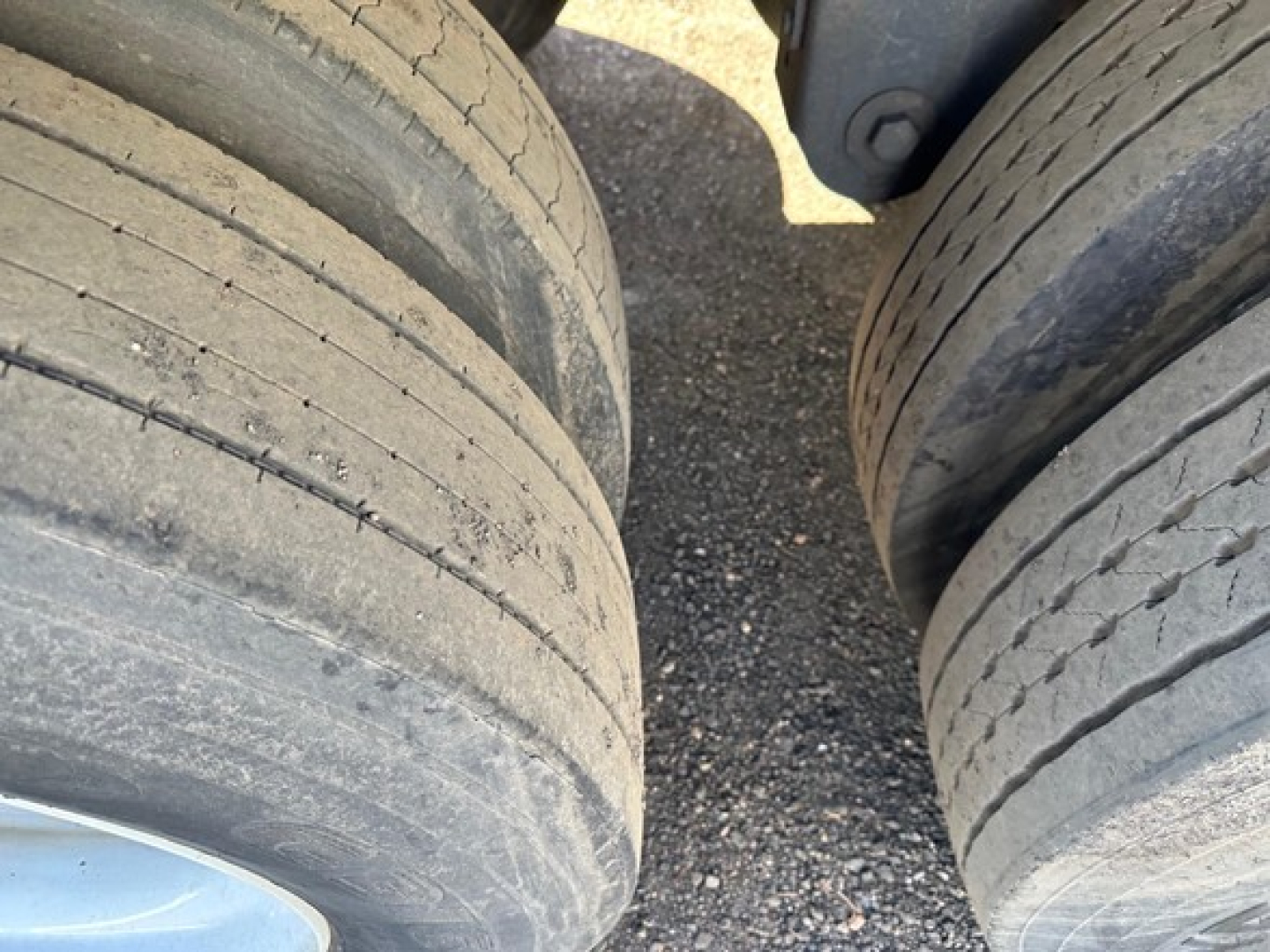 Trailer wheels showing dual axles with worn tires and light dust on surface.