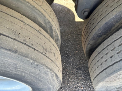 Trailer wheels showing dual axles with worn tires and light dust on surface.