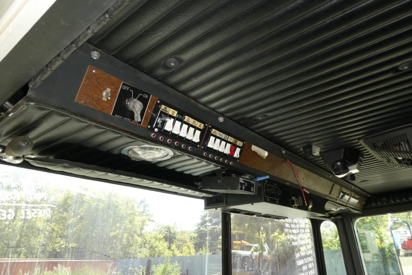 Fire truck cab interior showing control panel with switches, gauges, and wiring under a ribbed ceiling.