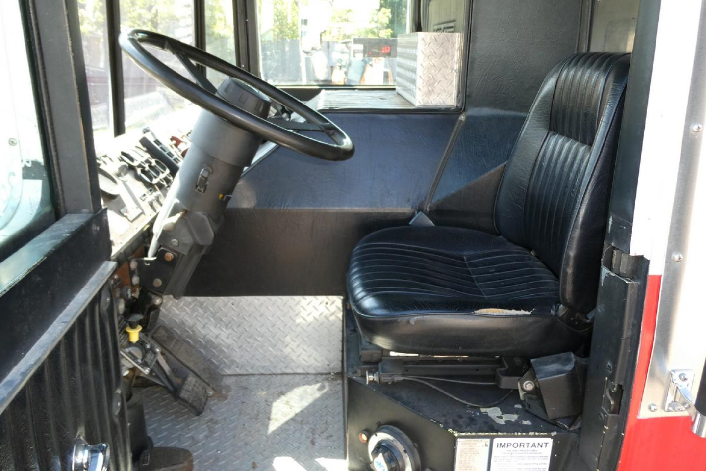 Cab interior of a 1991 KME fire truck showing steering wheel, driver's seat, and dashboard area.