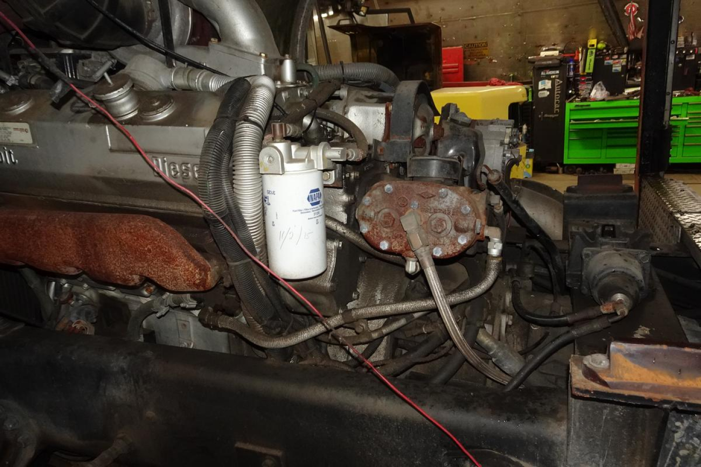 Diesel engine bay of 1991 KME fire truck showing coolant filter, turbo, belts, hoses, and exhaust manifold with electrical wiring.