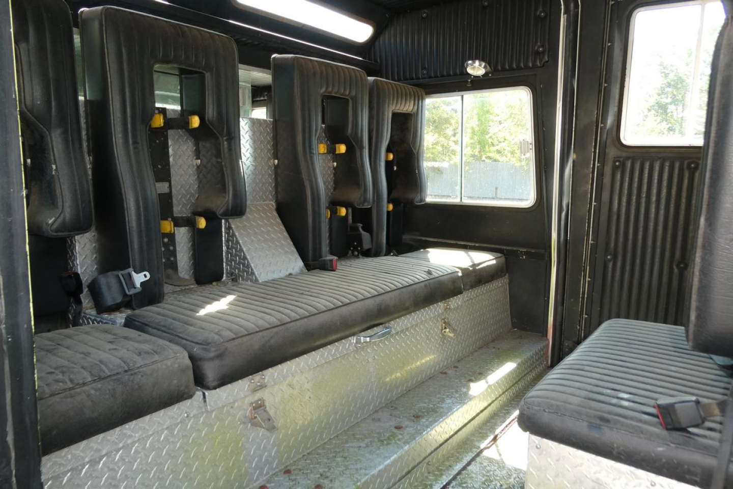 Interior of 1991 KME fire truck showing seating and cabin with diamond plate floor and black seats.