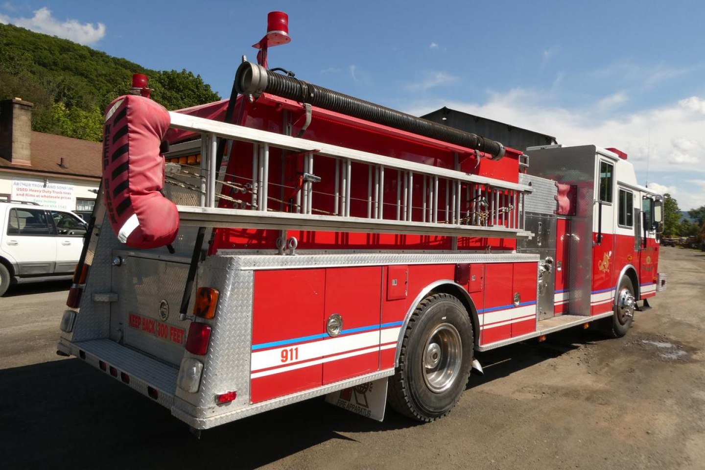 Fire truck in-service rear-right view with hoses and storage compartments visible.