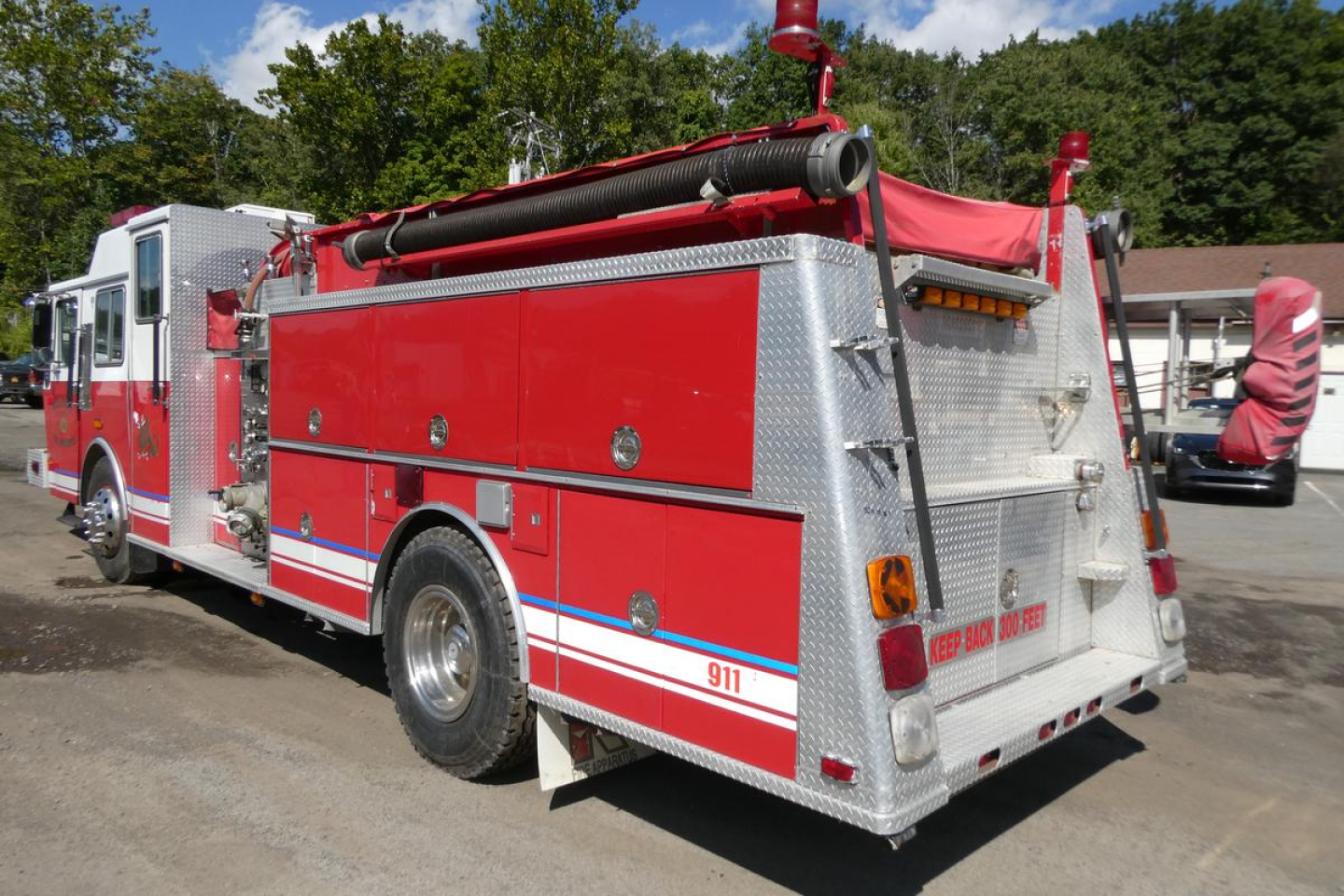 Red and silver 1991 KME fire truck rear view showing storage compartments and ladder.