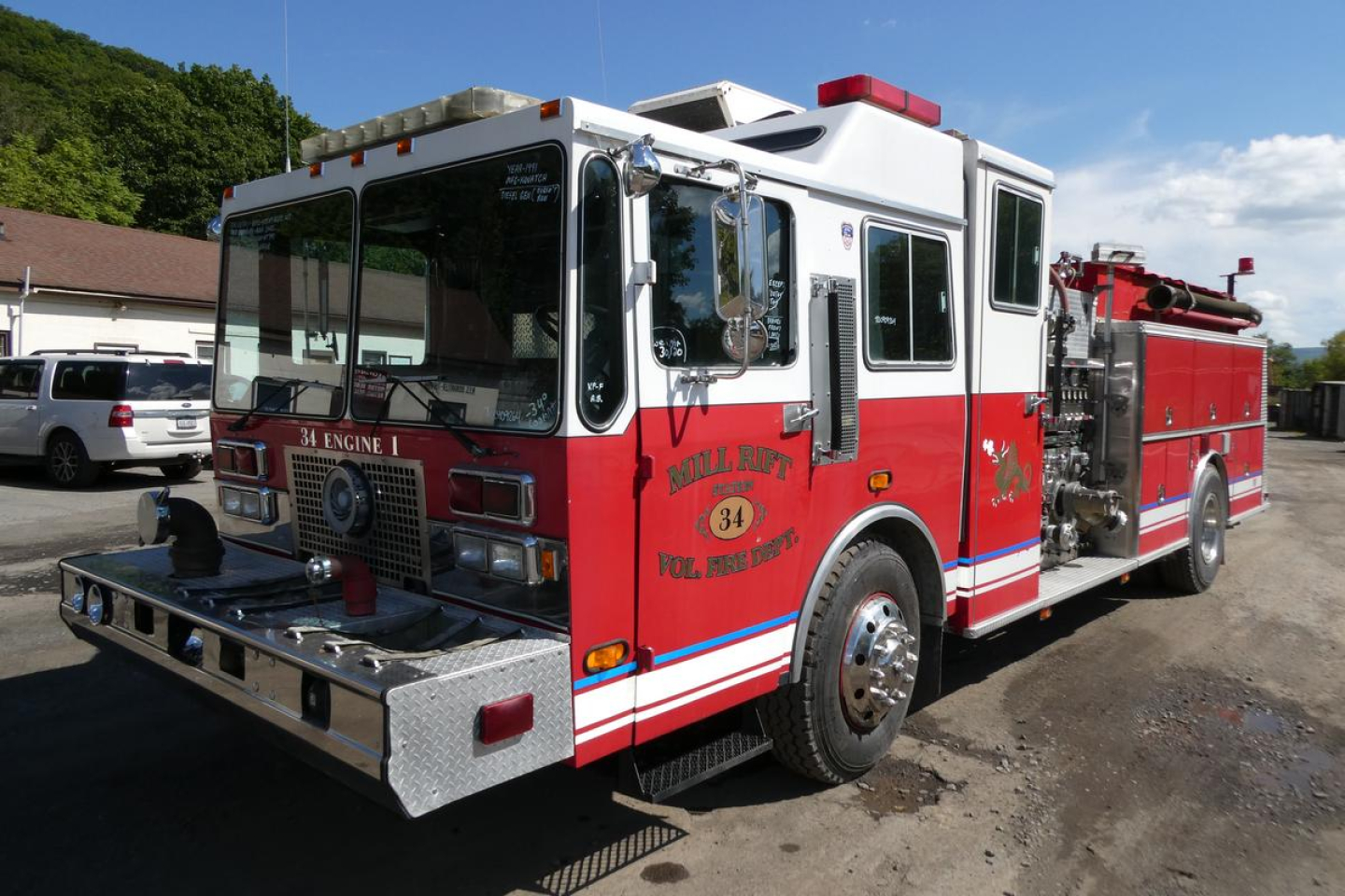 Fire engine truck with white cab and red body, front bumper, and equipment compartments visible; text on side reads Mill Run Vol Fire Dept 34; emergency lights on roof; VIN and stock info not visible.