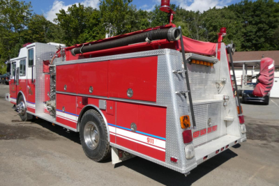 Red and silver 1991 KME fire truck rear view showing storage compartments and ladder.