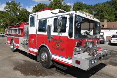 1991 KME fire truck side view showing pump panel, chrome bumper, and Mill Rift Fire Dept emblem on red and white body.