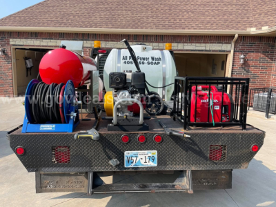 Back of a service truck showing a large metal platform with a water tank labeled All Power Wash 405-059-SOAP, a hose reel, and a Honda generator in a protective cage.