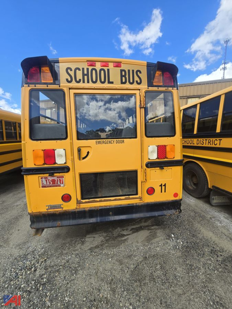 Rear view of a yellow Freightliner school bus labeled SCHOOL BUS with emergency door, taillights, and a number 11, parked beside another bus.