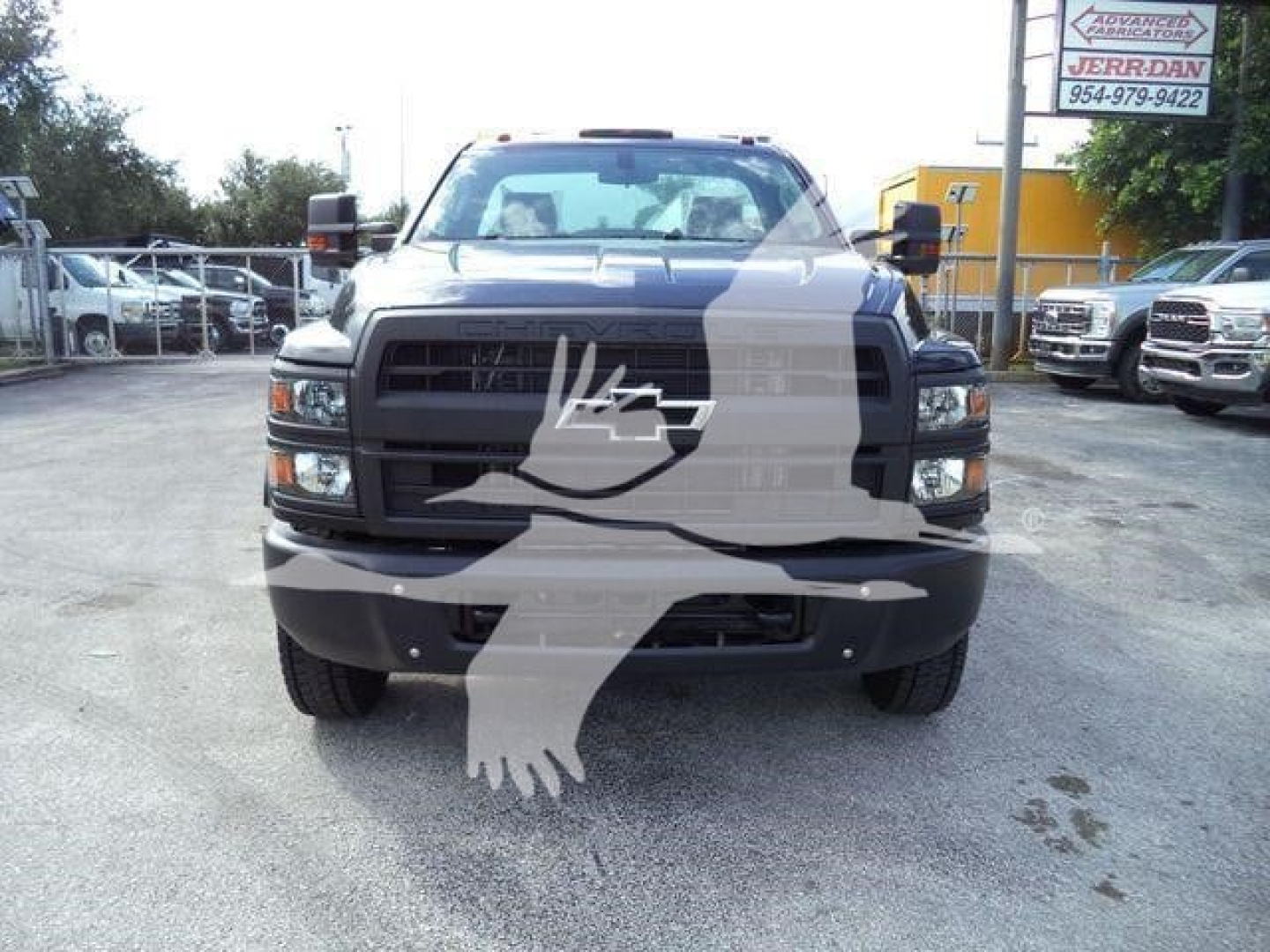 Front view of a black Chevrolet Silverado 6500HD rollback truck showing grille, headlights, bumper, and stock surroundings.
