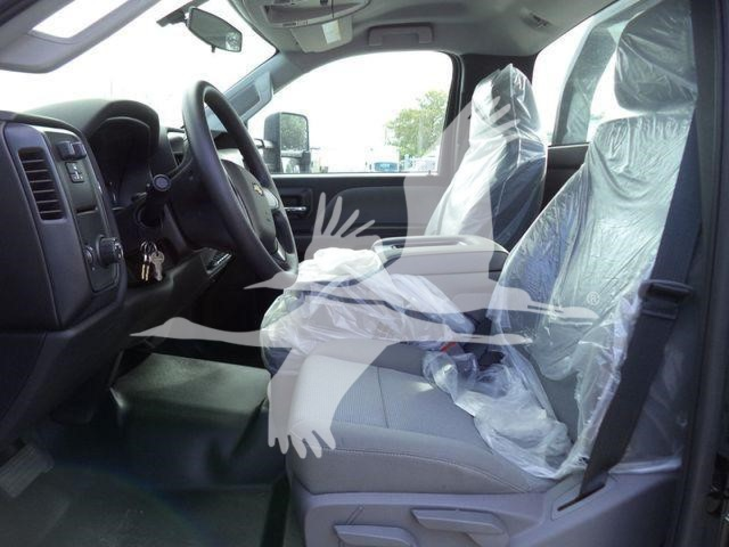 Truck interior showing front seats with protective plastic covers, steering wheel, dashboard, and driver-side door.